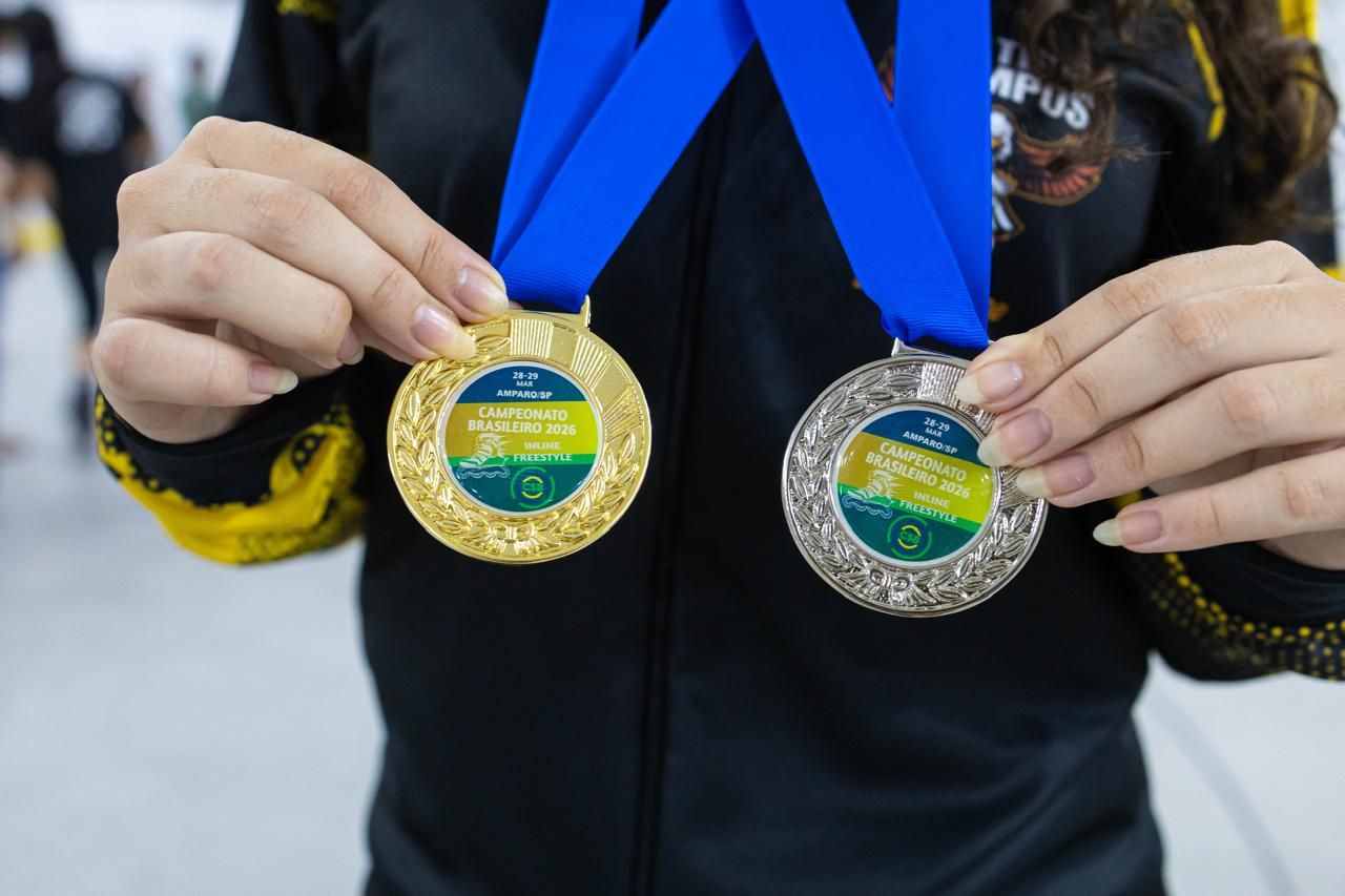 Mãos segurando uma medalha de ouro e uma de prata