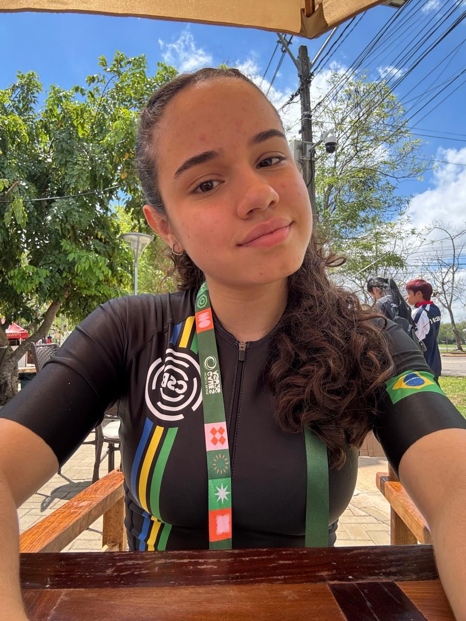 Selfie da Yasmin com a credencial do Mundial e a bandeira do Brasil no ombro