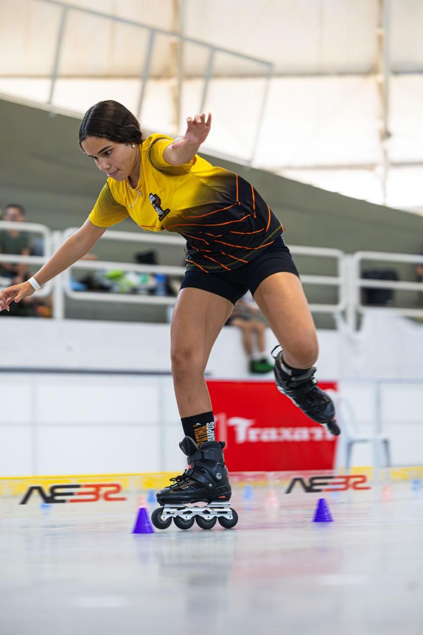 Yasmin inclinada sobre um patim, desviando dos cones na prova de slalom